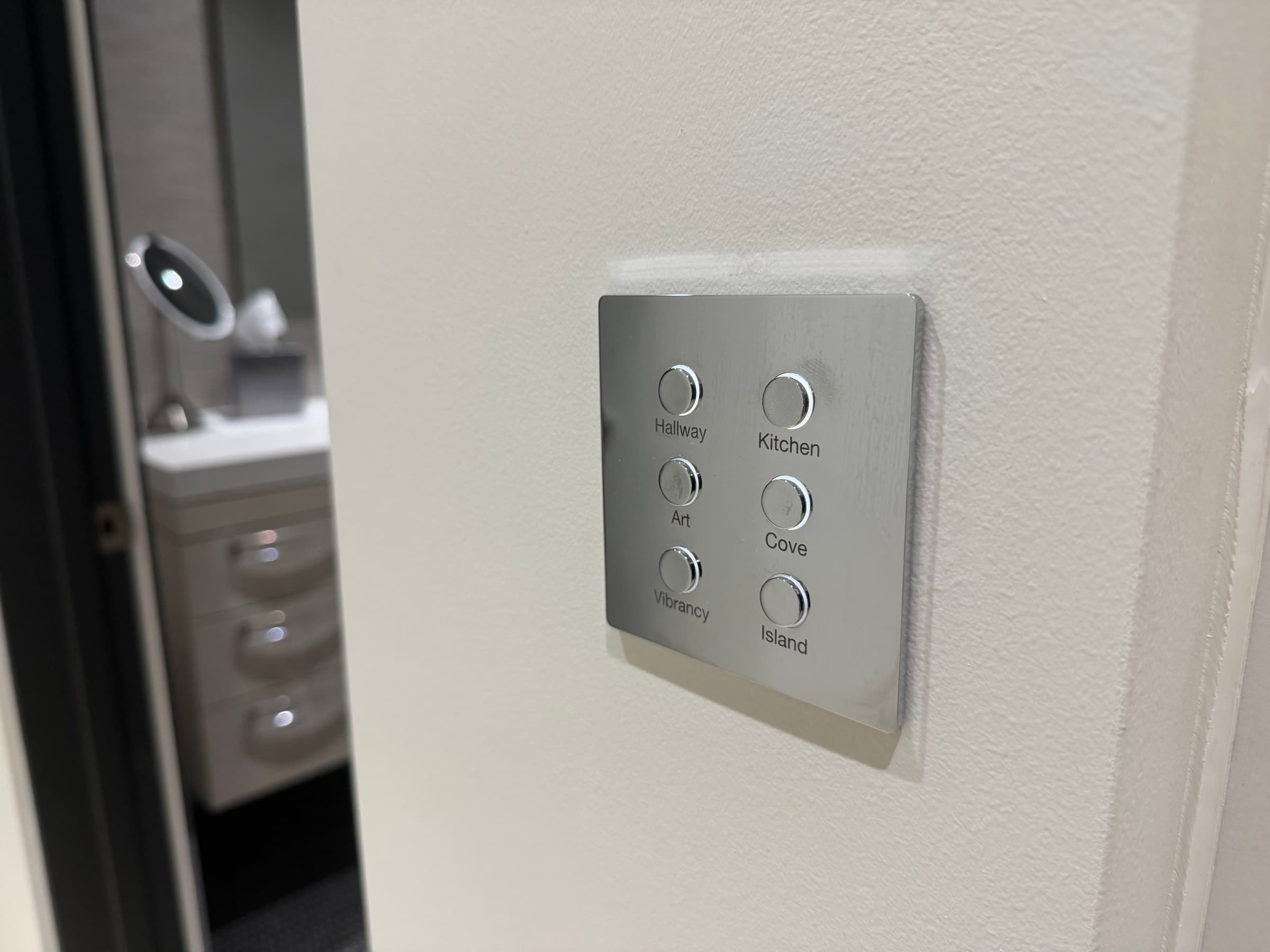 A brushed metal engraved lighting keypad on a white wall