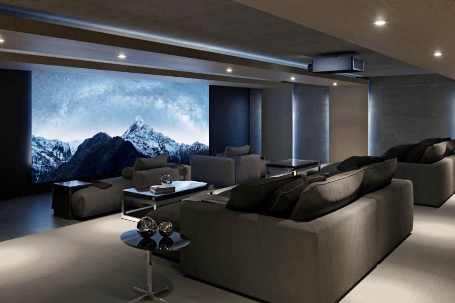 A home theater with a Sony projector and a large movie screen displaying snow-capped mountains.