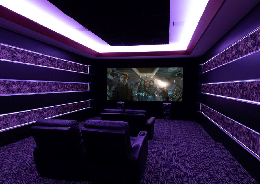 A home theater at Acoustic Designs Group Showroom with purple lighting, and in-ceiling and floorstanding speakers.