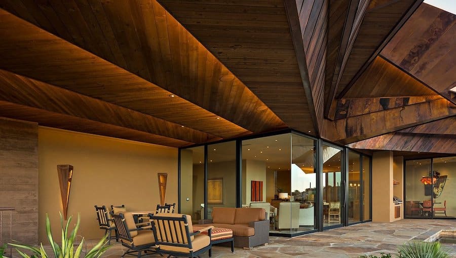 Outdoor patio area with in-ceiling speakers, couches, chairs, and an eye-catching wood ceiling