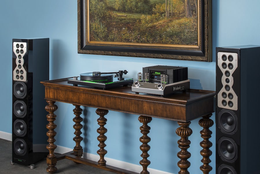 A McIntosh amplifier and turntable sitting on a credenza next to two loudspeakers