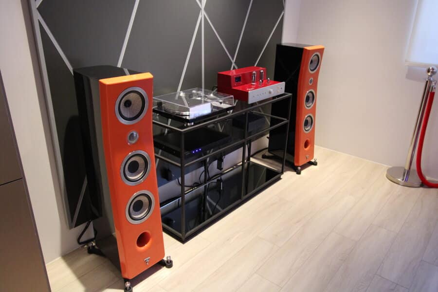 A high-end turntable on a table with two standing speakers at each side.