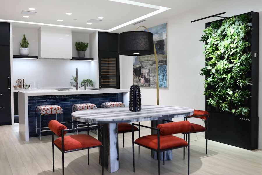 modern kitchen island and table with red upholstery in front of a 3D plant wall